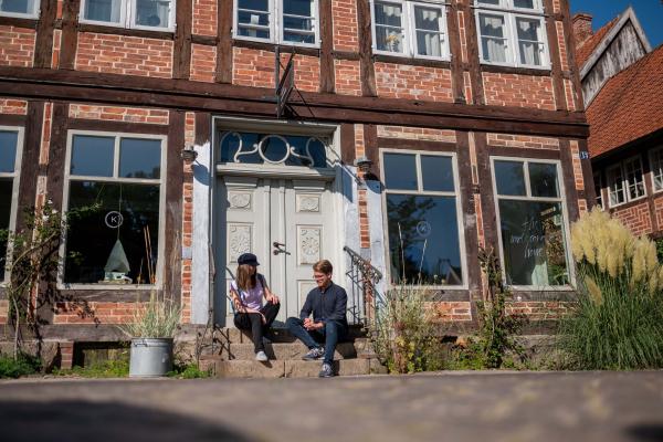 Zwei Personen sitzen auf den Stufen vor einer Haustür in der Eutiner Stolbergstraße