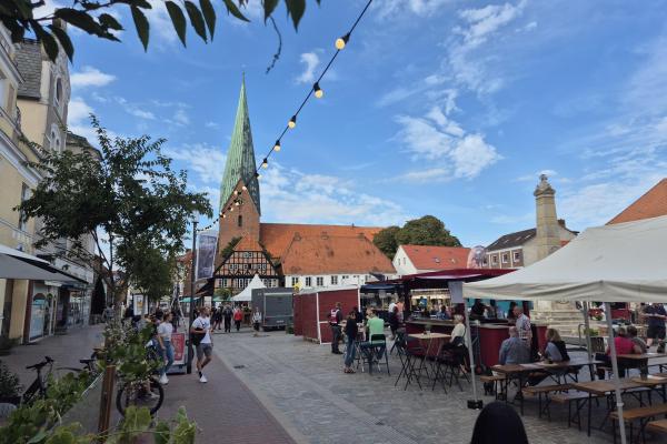 Biergartenlichterketten leuchten auf dem Marktplatz während des Weinfestes. Blick auf die Kirche.