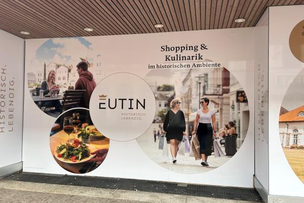 Schaufenster Folierung Shopping und Kulinarik Blick auf fertige Folierung von leerstehenden Schaufenstern mit Abbildung von möglichen Angeboren, wie Shopping oder Kulinarik